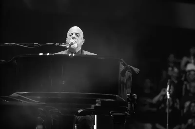 Image: Billy Joel sings and plays piano.