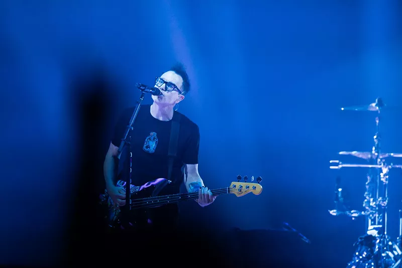 Image: A man singing and playing bass.