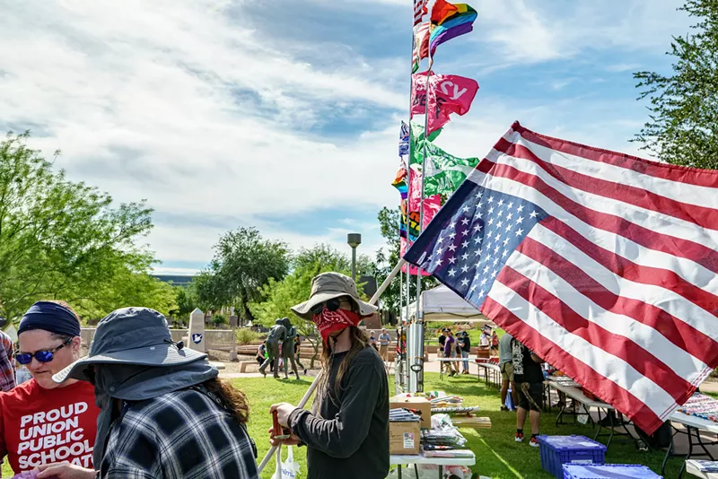 Image: a protester with his face covered by a bandana holding up an upside-down U.S. flag