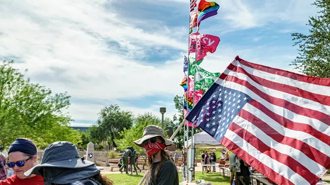 a protester with his face covered by a bandana holding up an upside-down U.S. flag