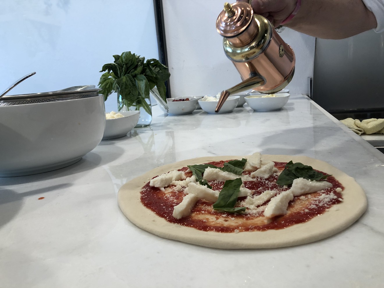 Topping a margherita pizza with olive oil.