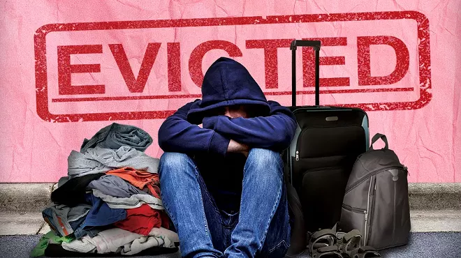 a person in a hoodie sitting depressed with luggage and clothes on the curb, with a superimposed eviction notice behind