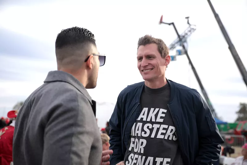 Image: Blake Masters speaks with attendees at a "Save America" rally at Country Thunder Arizona in Florence on January 15.