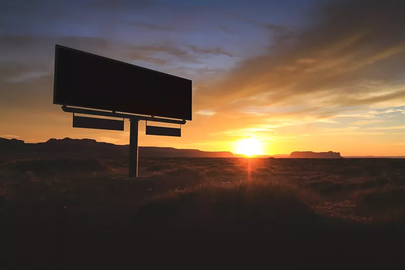 Image: a billboard backlit by an arizona sunset