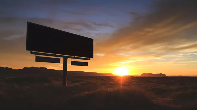 a billboard backlit by an arizona sunset