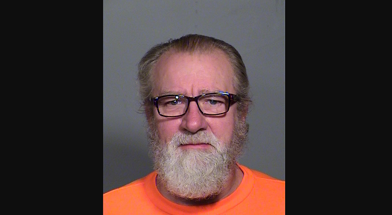 Image: a mugshot of a bearded man in glasses