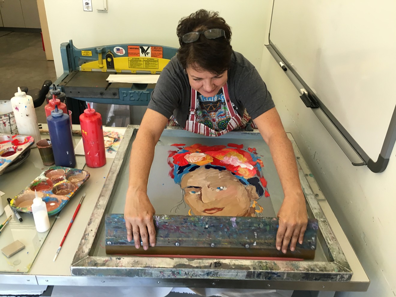 Emily Costello pulling a print of Frida Kahlo in an art studio at Mesa Arts Center.