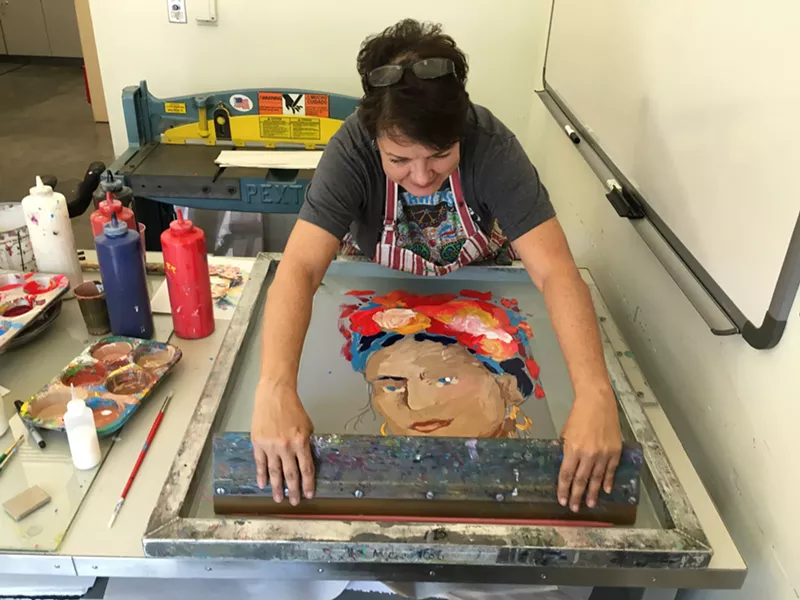 Image: Emily Costello pulling a print of Frida Kahlo in an art studio at Mesa Arts Center.