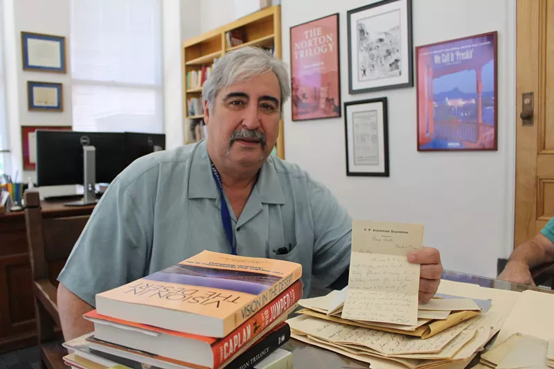 Image: Professor Jack August in his office at the Arizona Capitol Museum, with a letter from former Governor Fife Symington's collection.