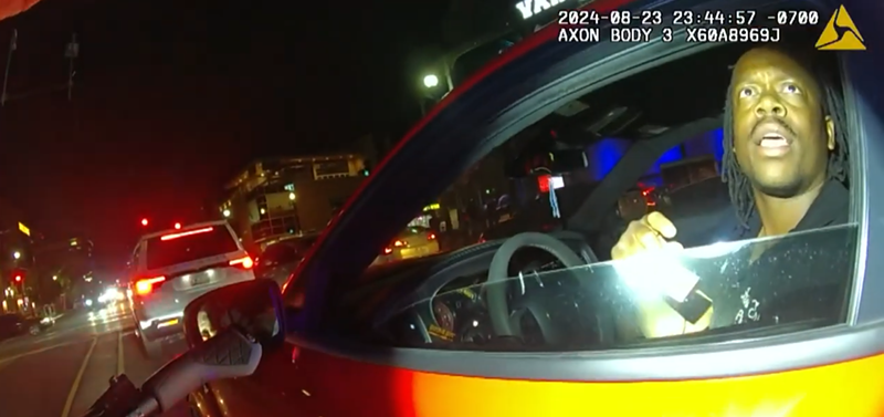 Image: body-cam footage of a flashlight being shined on a man in a car