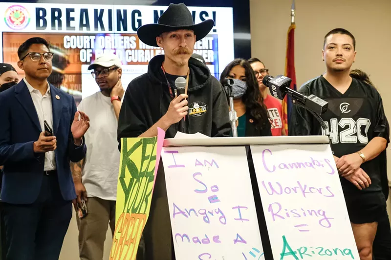 Image: a man in a cowboy hat speaks at a press conference