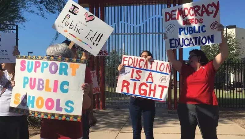 Image: Save Our Schools Arizona volunteers stand outside of the Arizona School for the Arts to show their disdain for a controversial school voucher law Governor Doug Ducey signed.