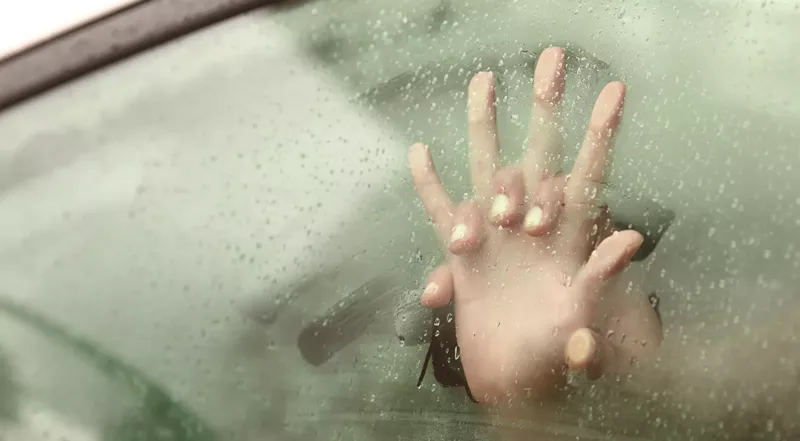 Image: two intertwined hands against a steamy car window