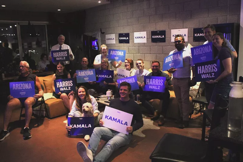 Image: Guests for the LDS Advisory Committee Vice Presidential Debate watch party pose for a photo while holding Harris-Walz campaign signs