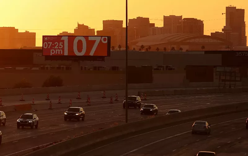 Image: a phoenix highway with a billboard reading 107 degrees at 7:25 p.m.