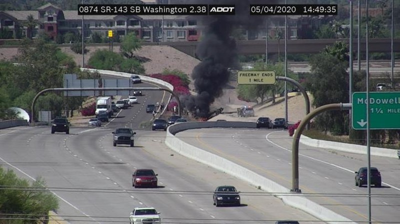 A Garda armored vehicle burns after rolling over on the Loop 202 freeway on Monday. A passenger died in the crash, which is under investigation.