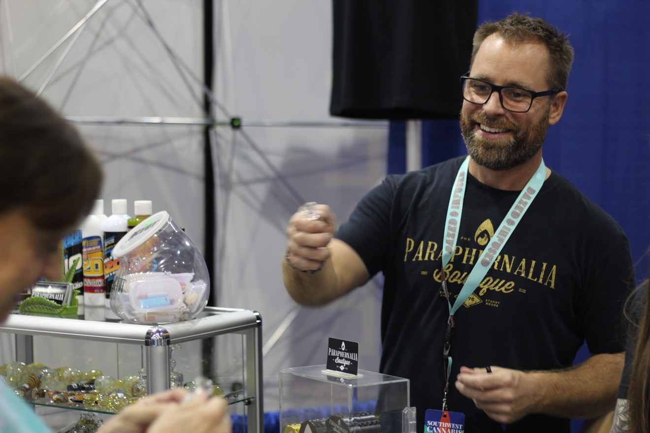 Chris Morris of Phoenix smokeshop Paraphernalia Boutique shows some of his glassware to a customer. The company was among more than 100 with booths at the SWCC Expo on Friday and Saturday.