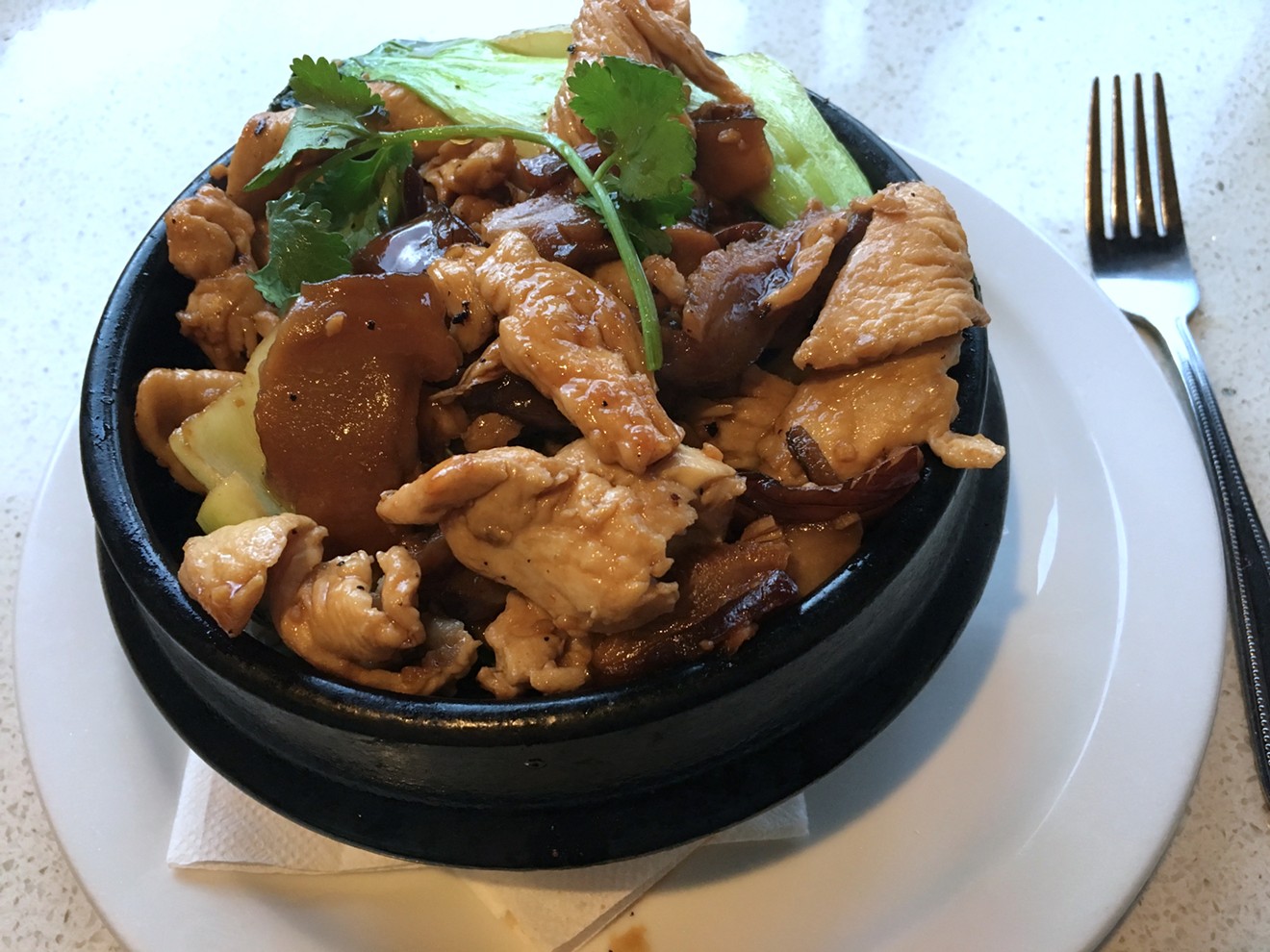 Chicken, jasmine rice, and vegetables in a sizzling clay pot.