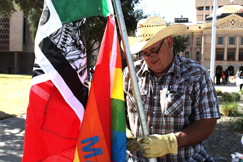 Image: a man strings a flag onto a pole