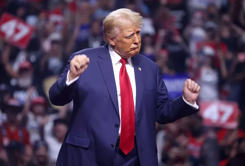 Image: A political candidate in a suit dances in front of a large crowd.