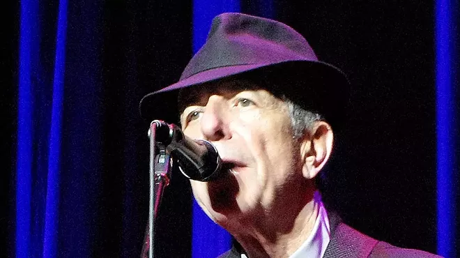 A man in a porkpie hat sings into a microphone.