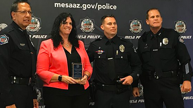 a woman holds an award while posing for a photo with police