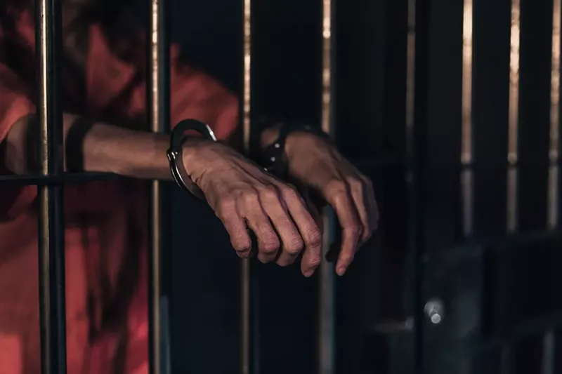 Image: Handcuffed hands stick outside prison bars