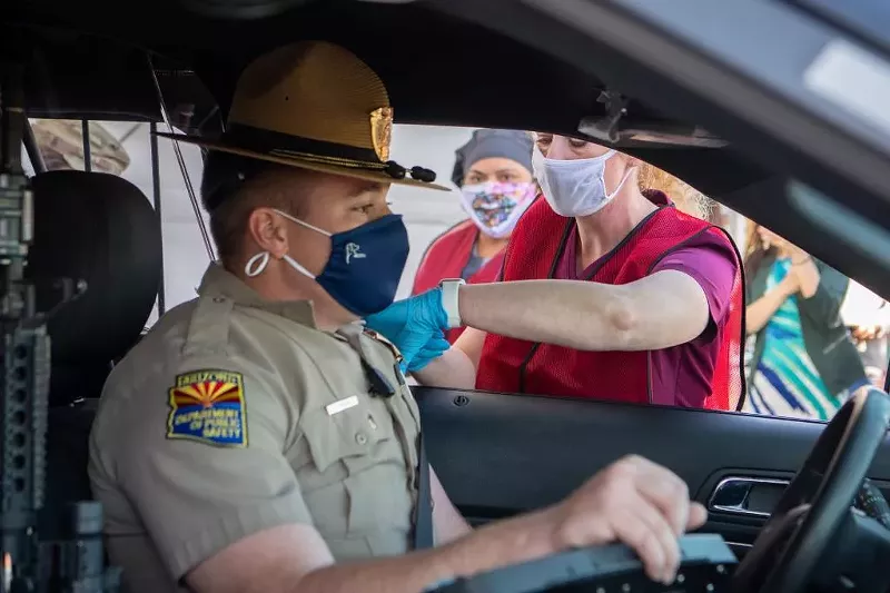 Image: A state trooper receives a vaccination from ADHS head Cara Christ in January.