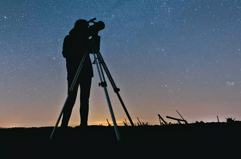 Image: A person looking through a telescope.