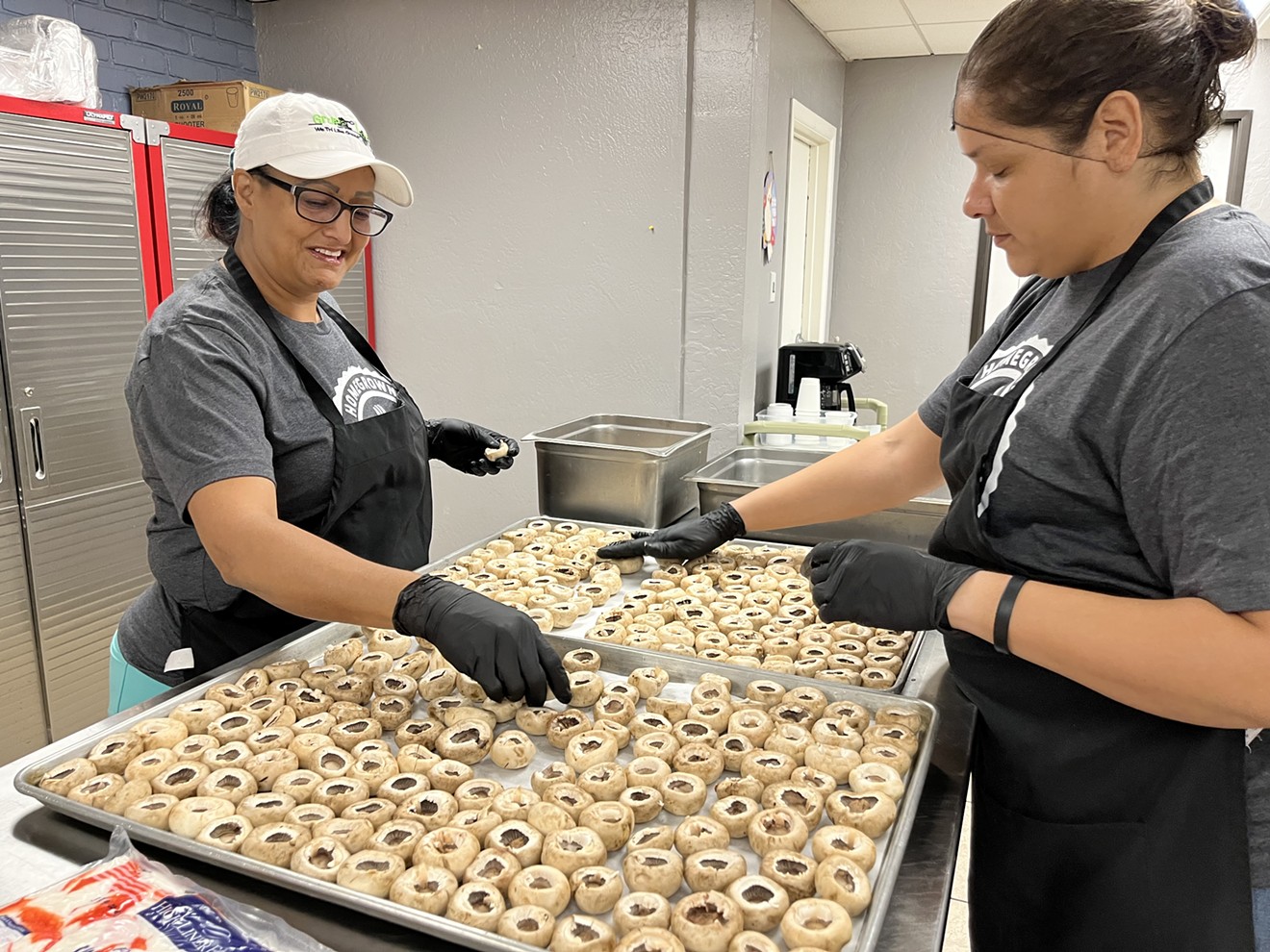 Culinary students Mercedes Sandoval (left) and Sophia Leon prepare mushrooms that will be stuffed with crab and served at the program’s graduation event.