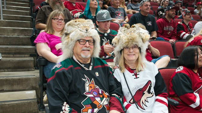 Two Arizona Coyotes fans sit in jerseys and custom, furry Coyotes hats.