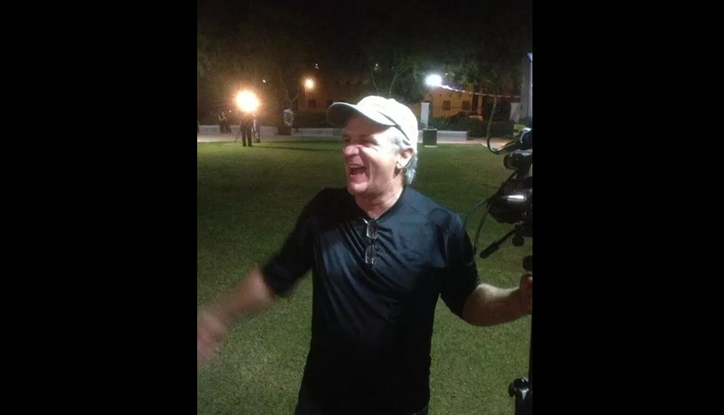 Image: a man smiles at night holding a video camera