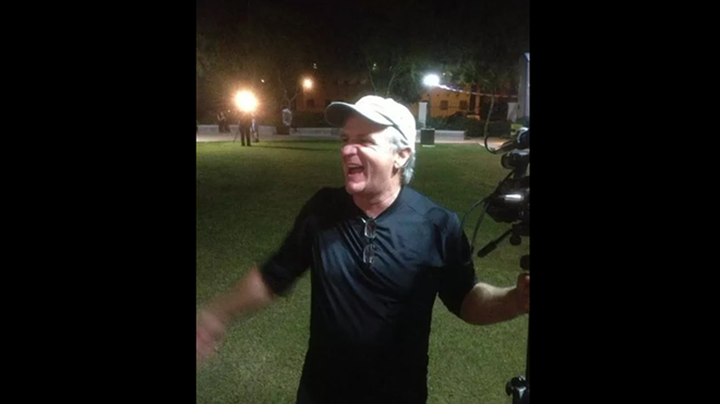 a man smiles at night holding a video camera