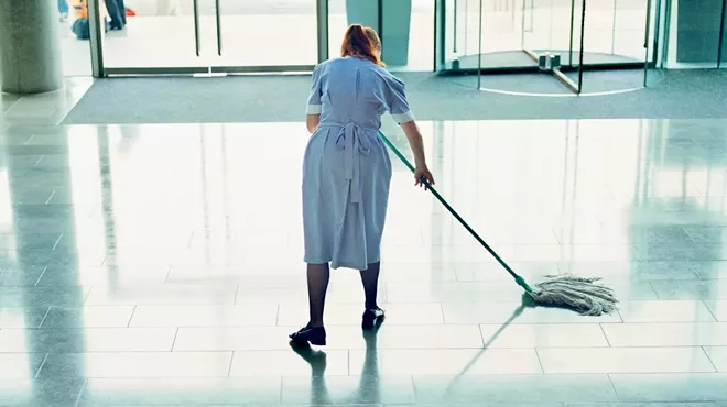 A hotel housekeeper mopping a lobby floor