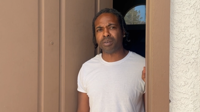 a man in a white shirt standing in an open doorway