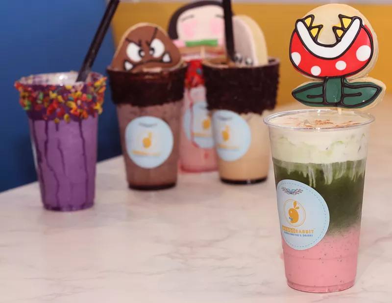 Image: The Piranha Plant drink (forefront) is a three-layered strawberry matcha drink topped with a cookie.