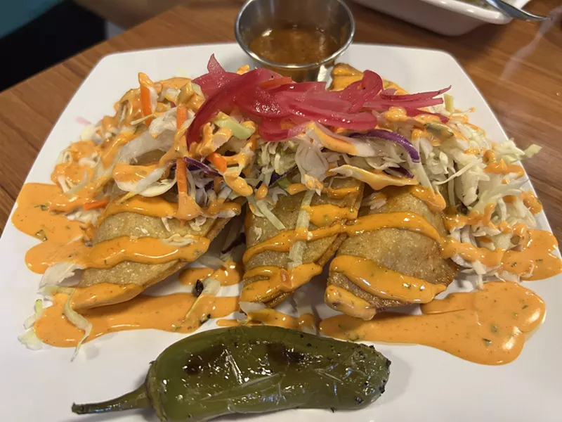 Image: Shrimp Crunchy Tacos with fresh cabbage, drizzled with house-made Sriracha sauce with a side of pickled onions and a roasted jalapeno