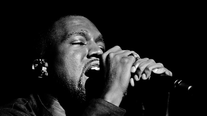 Kanye West singing into a microphone.