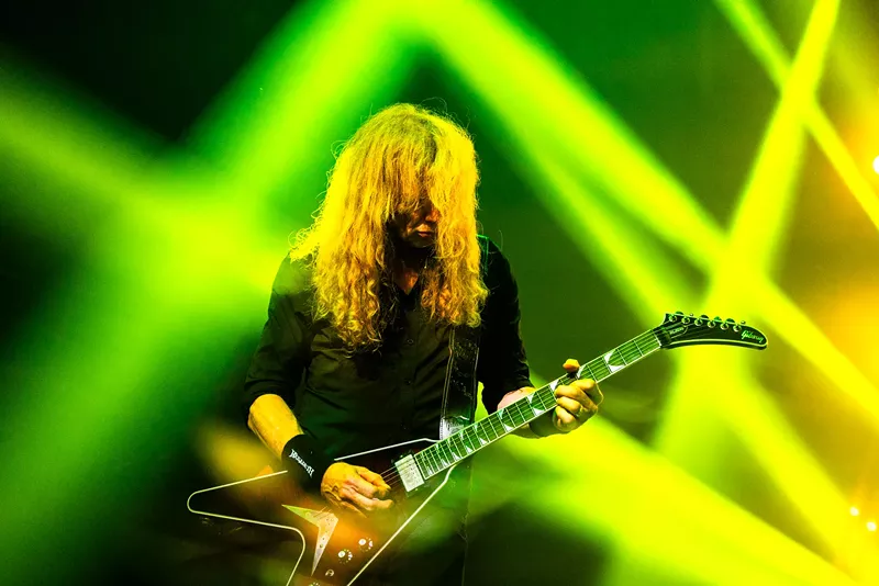 Image: A man with long hair plays guitar.