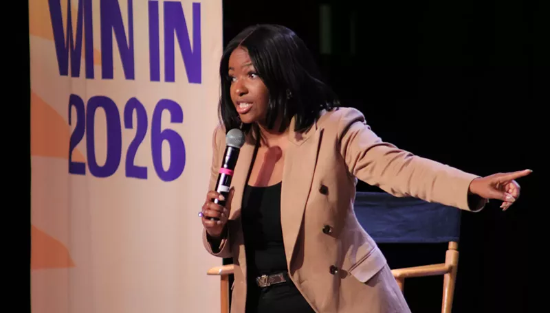Image: jasmine crockett speaks into a microphone and points off to her side