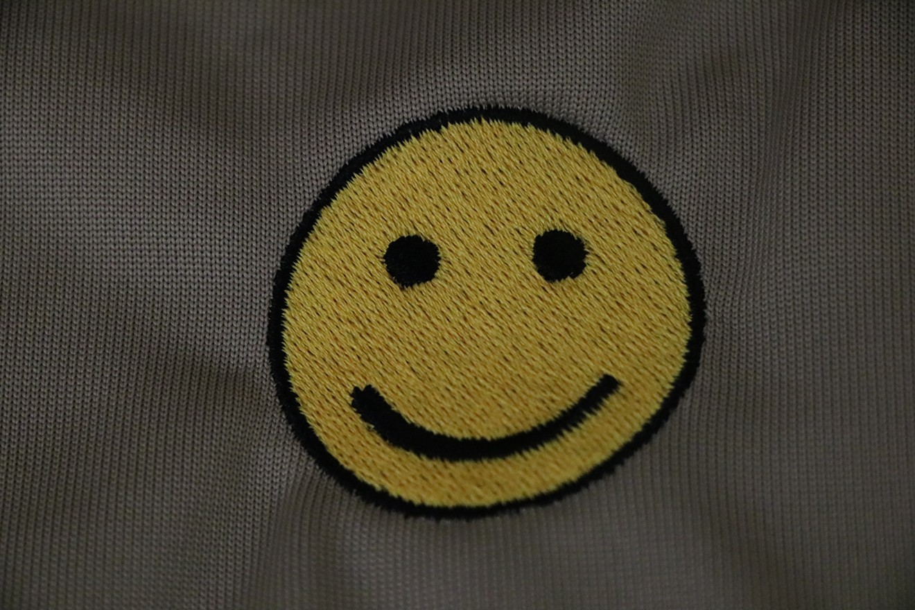 Smiley faces stitched on the back of hundreds of Arizona Department of Economic Security uniforms will be covered with Arizona flags, the agency said on Thursday.