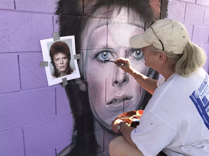 Image: Phoenix artist Maggie Keane refreshing a panel of her mural that got tagged earlier this year.