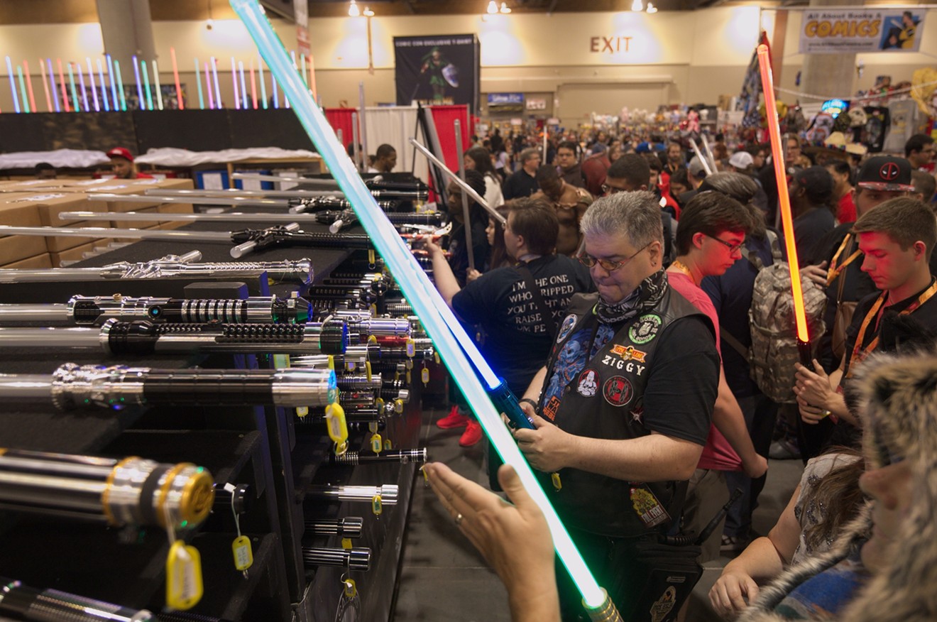 Phoenix Comicon attendees check out lightsabers for sale in the Exhibitor Hall on Thursday.