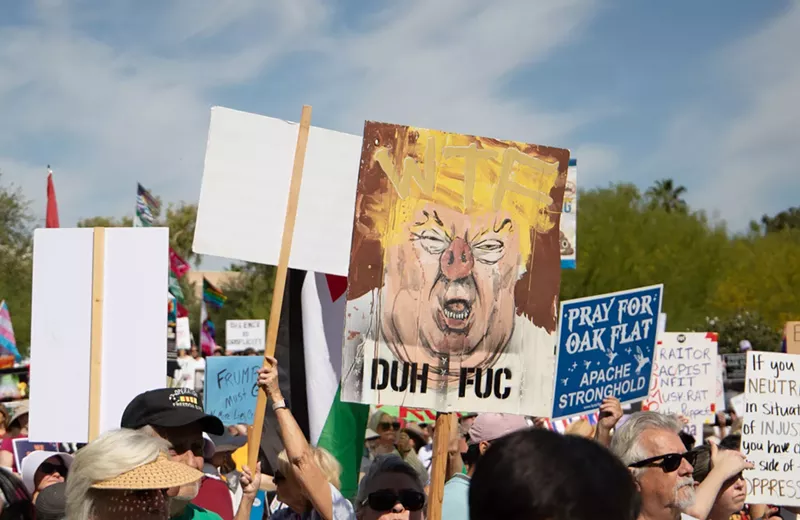 Image: a protest sign with donald trump painted a bit like a pig, with the words "duh fuc"
