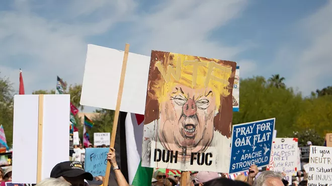 a protest sign with donald trump painted a bit like a pig, with the words "duh fuc"