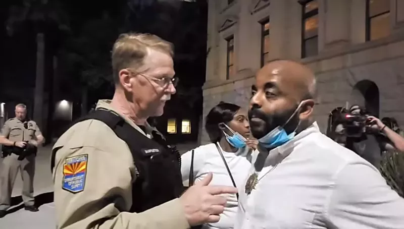 Image: Jarrett Maupin speaks with an Arizona Department of Public Safety Officer at Thursday's protest.