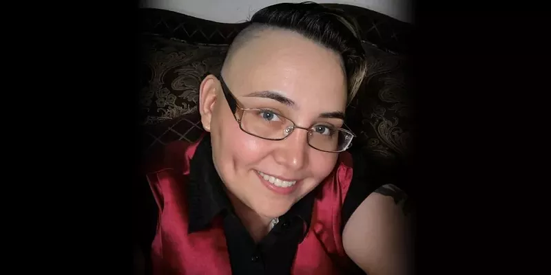 Image: a woman with close-cropped hair and glasses in a selfie