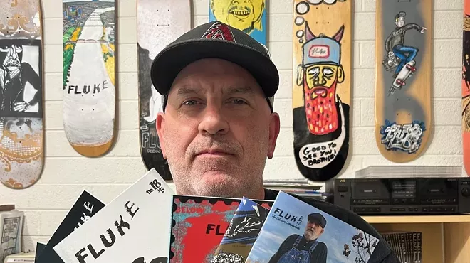 A man in a hat holding up a selection of zines.