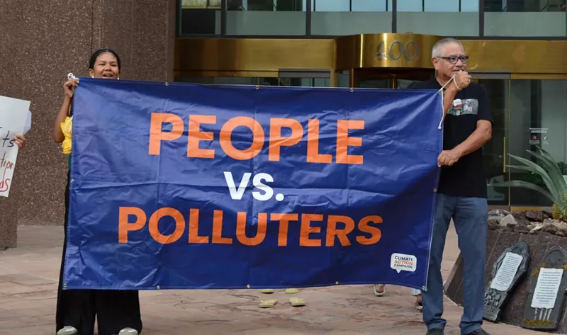 Image: Protesters stand outside of Arizona Power Service’s headquarters on Thursday after the utility’s recent decision to walk back its clean energy goals.