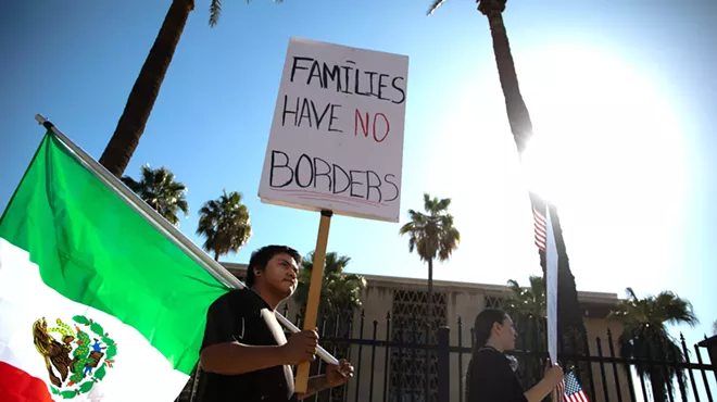 a protester holds a mexican flag and a sign that says" families have no borders"